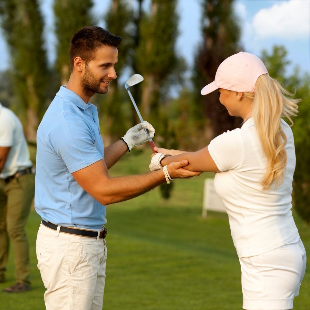 golfunterricht für frauen in berlin und brandenburg. es ist ein golflehrer mit seiner schülerin zu sehen. er bringt ihr das golf spielen bei.